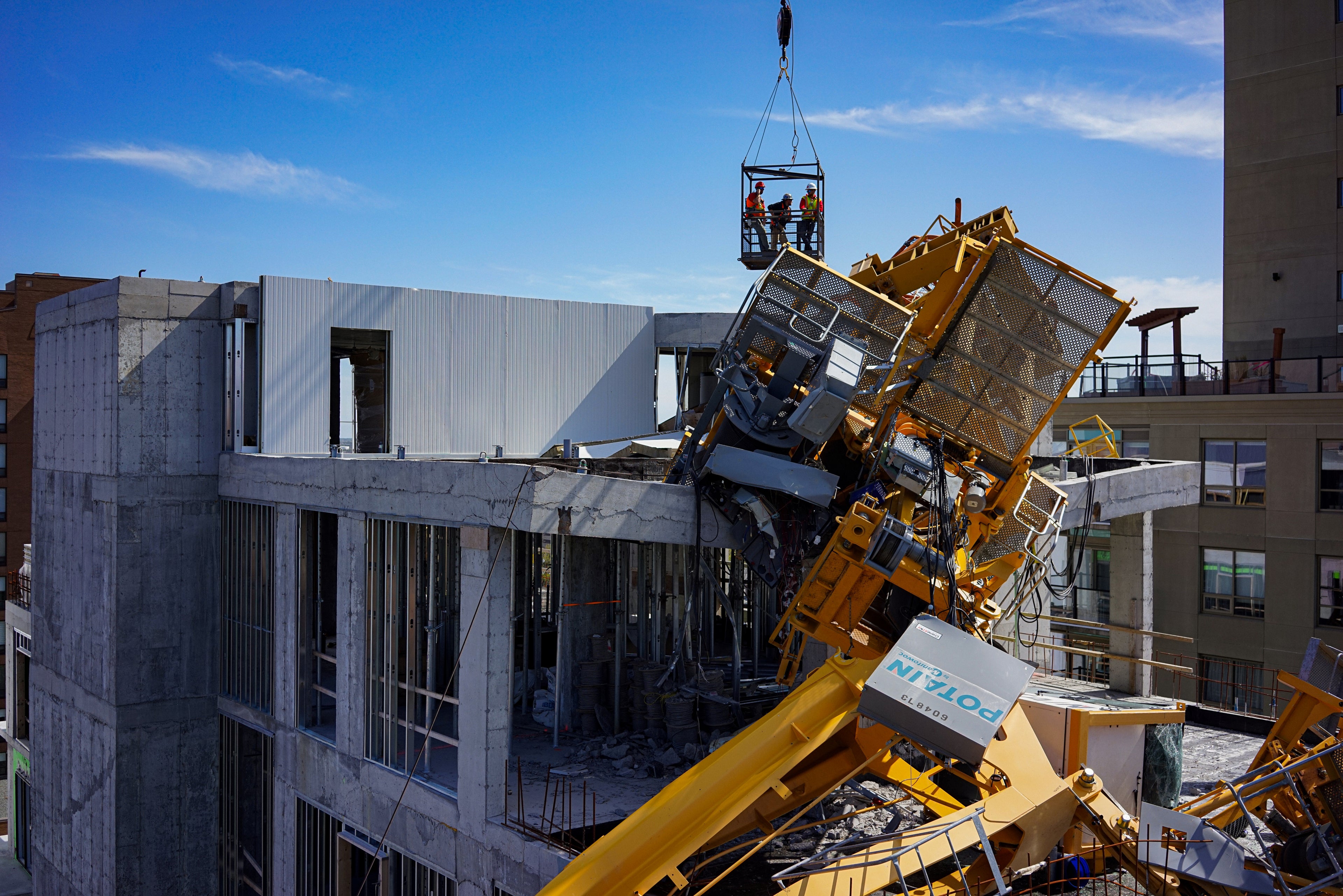 Construction site with fallen crane against a blue sky.