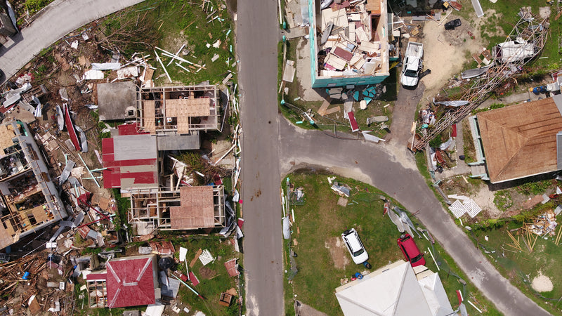 Top down view of the after math of a destructive hurricane. Houses seen with their roofs torn apart, debris seen everywhere.