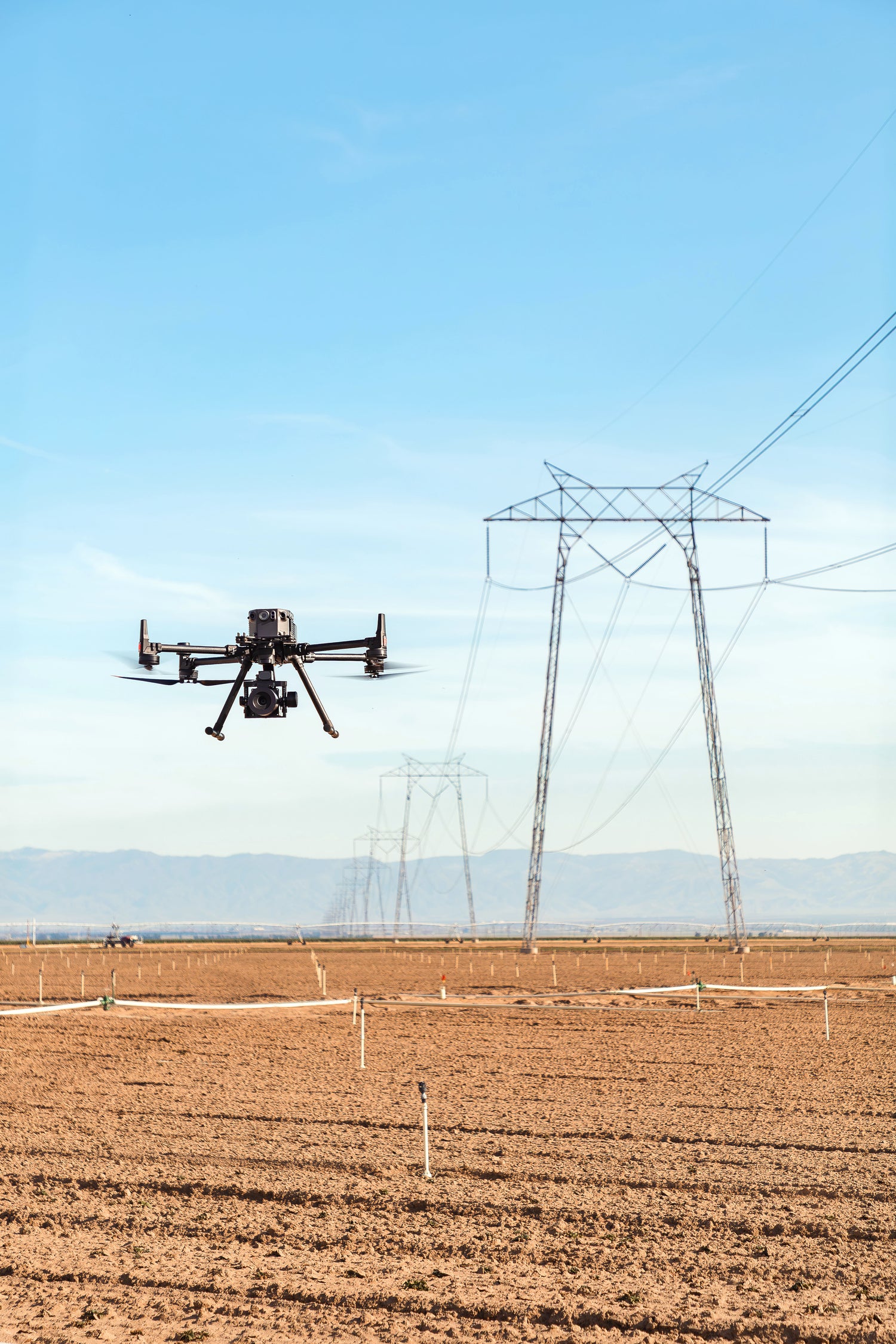 Drone flying over a field with power lines in the background