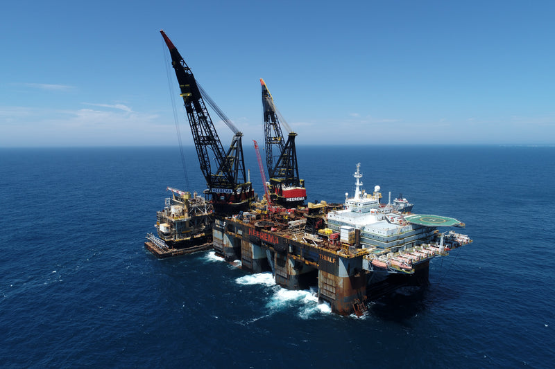 Large offshore oil platform with cranes in the middle of the ocean.